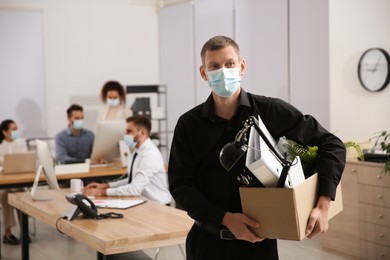 Upset dismissed man carrying box with stuff in office, space for text