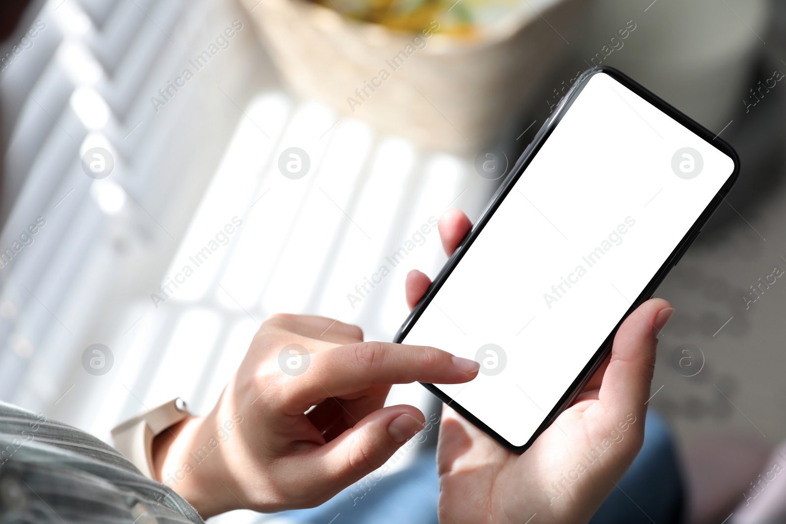 Image of Woman holding mobile phone with empty screen indoors, closeup