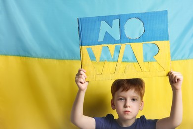 Photo of Boy holding poster No War against Ukrainian flag, space for text