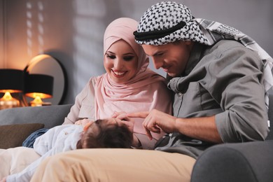 Happy Muslim family with little son in living room