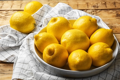 Photo of Plate with whole lemons on wooden background