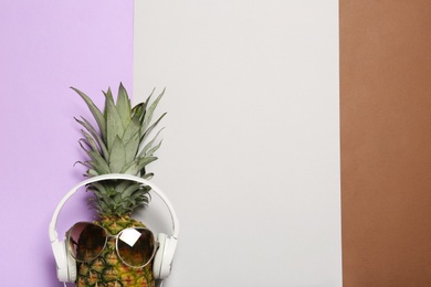 Photo of Funny pineapple with headphones and sunglasses on color background, top view. Space for text