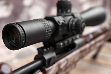 Photo of Closeup view of modern powerful sniper rifle with telescopic sight on blurred background