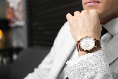 Photo of Businessman with luxury wrist watch on blurred background, closeup. Space for text