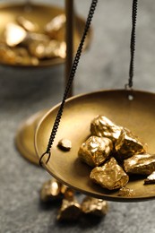Photo of Vintage scales with gold nuggets on grey table, closeup