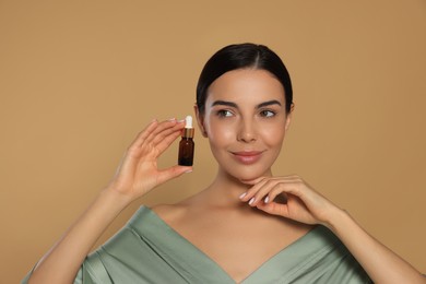 Photo of Young woman with bottle of essential oil on beige background