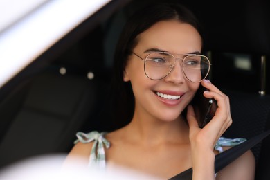 Photo of Happy young woman talking on smartphone in modern car, view from outside