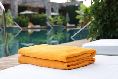 Photo of Beach towels on sun lounger near outdoor swimming pool. Luxury resort