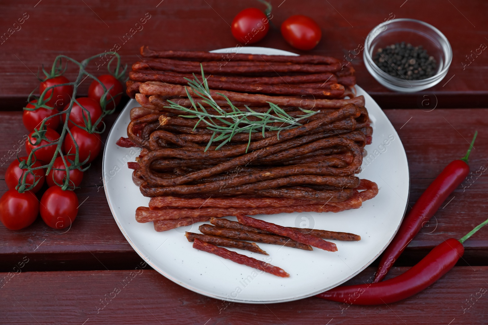 Photo of Tasty dry cured sausages (kabanosy) and ingredients on wooden table, flat lay