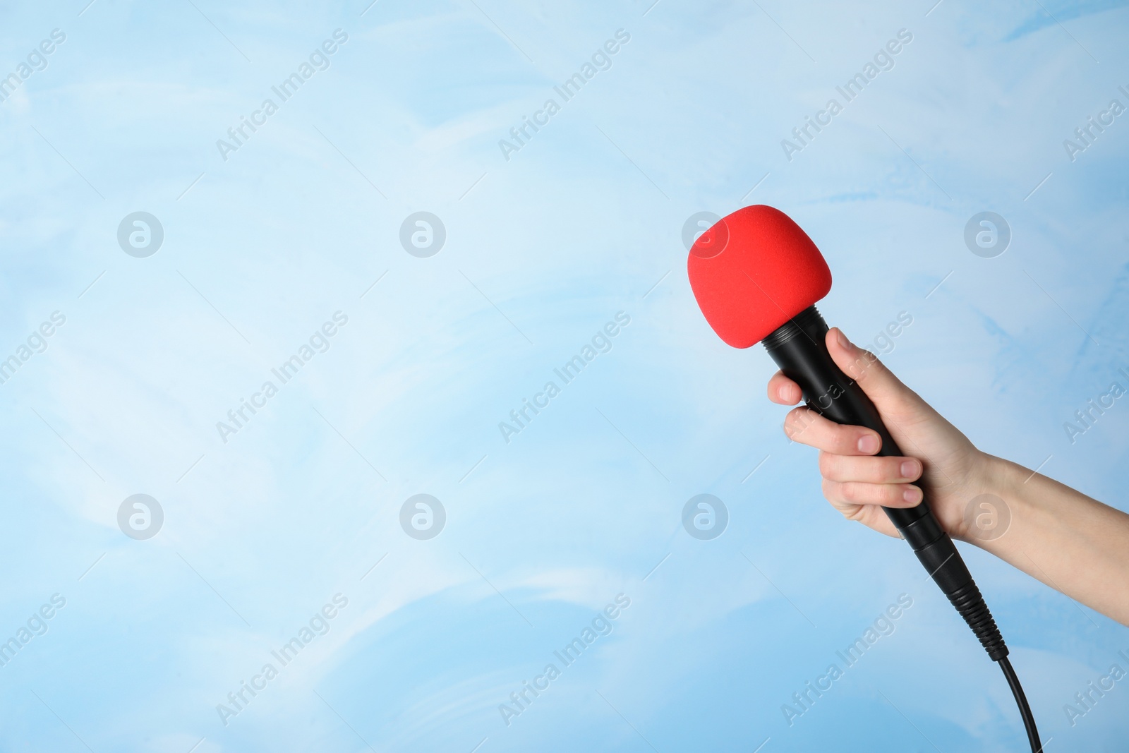 Photo of Woman holding modern microphone on color background, closeup. Space for text