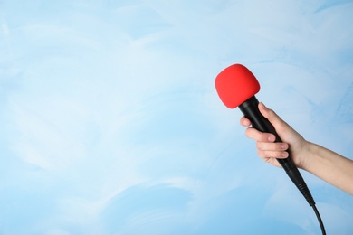 Woman holding modern microphone on color background, closeup. Space for text