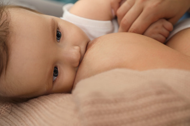 Photo of Woman breastfeeding her little baby, closeup view