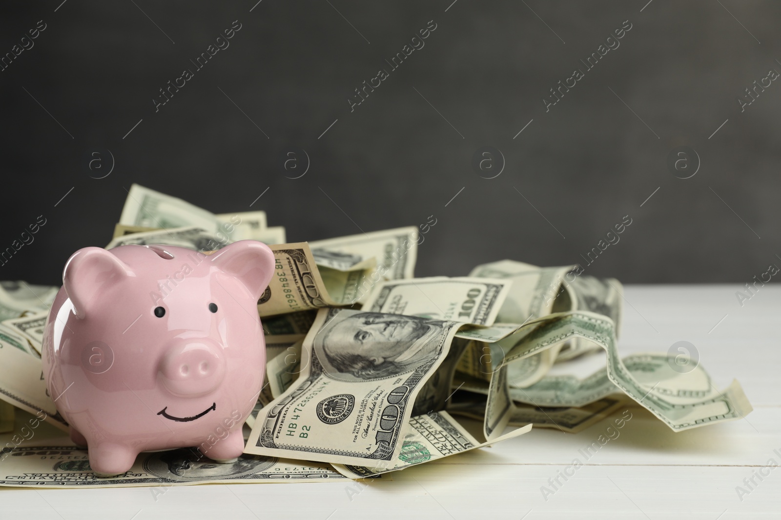 Photo of Money exchange. Dollar banknotes and piggy bank on white wooden background, space for text