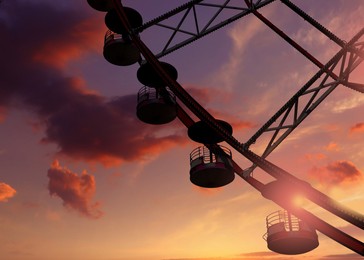 Image of Beautiful large Ferris wheel outdoors at sunset
