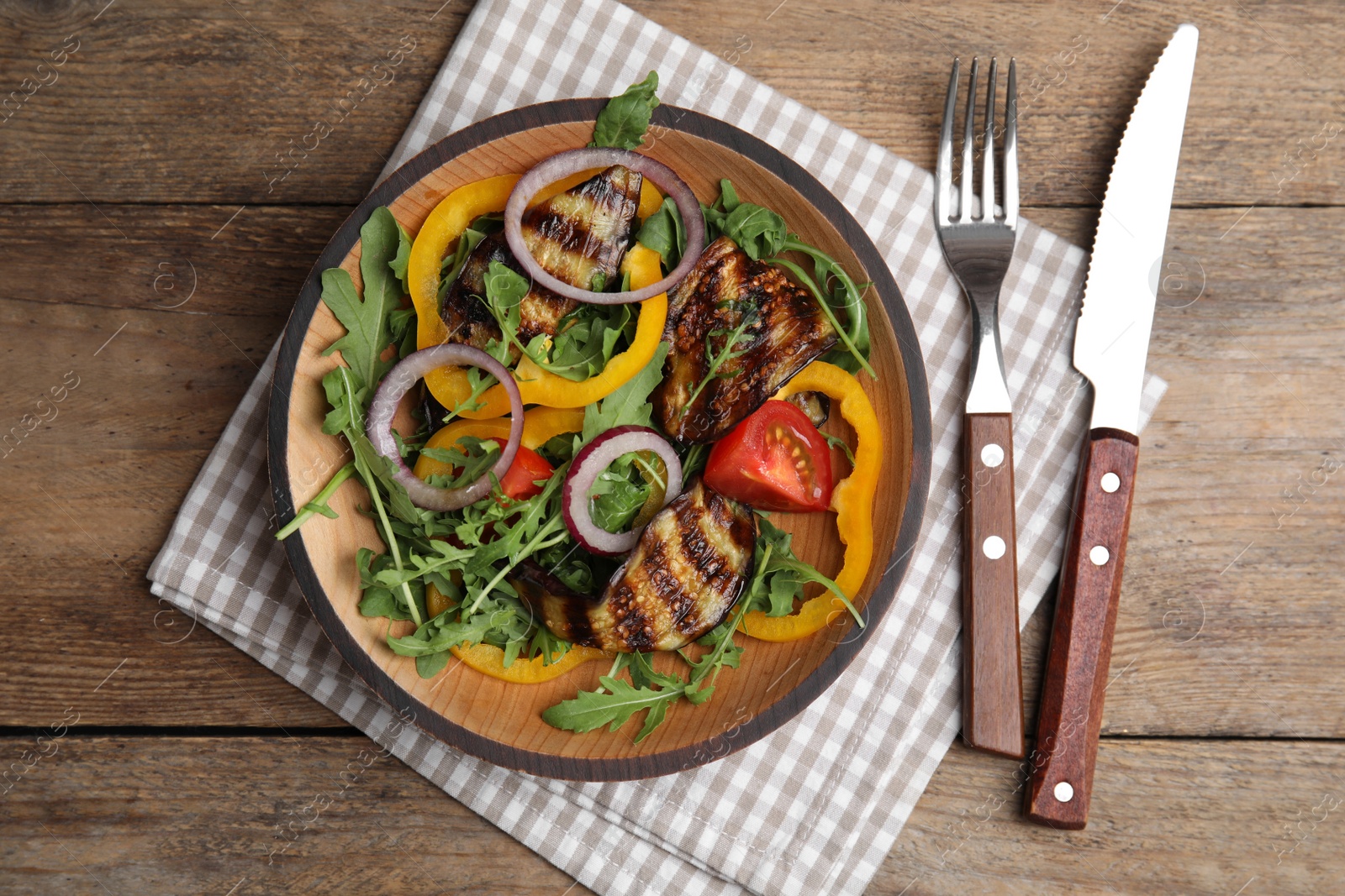 Photo of Delicious salad with roasted eggplant and arugula served on wooden table, flat lay