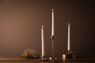 Photo of Elegant candlesticks with burning candles on wooden table