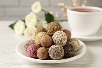 Delicious vegan candy balls on white wooden table against blurred lights