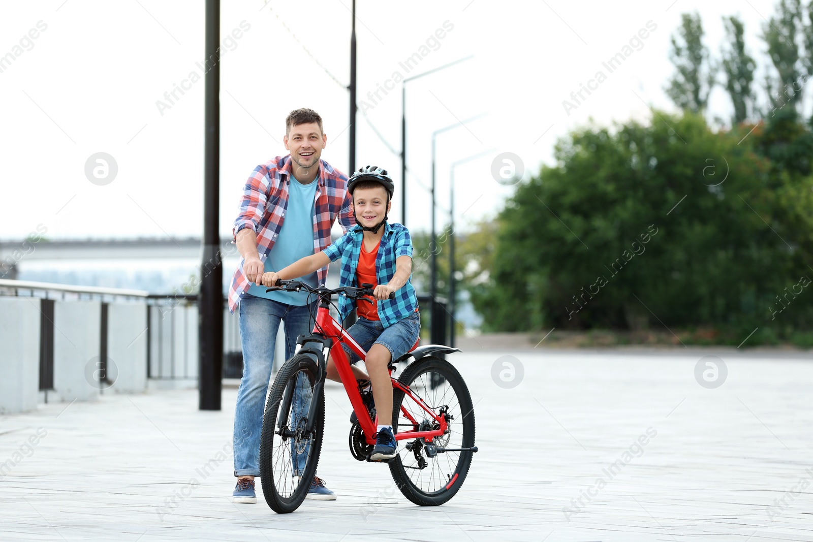 Photo of Dad teaching son to ride bicycle outdoors