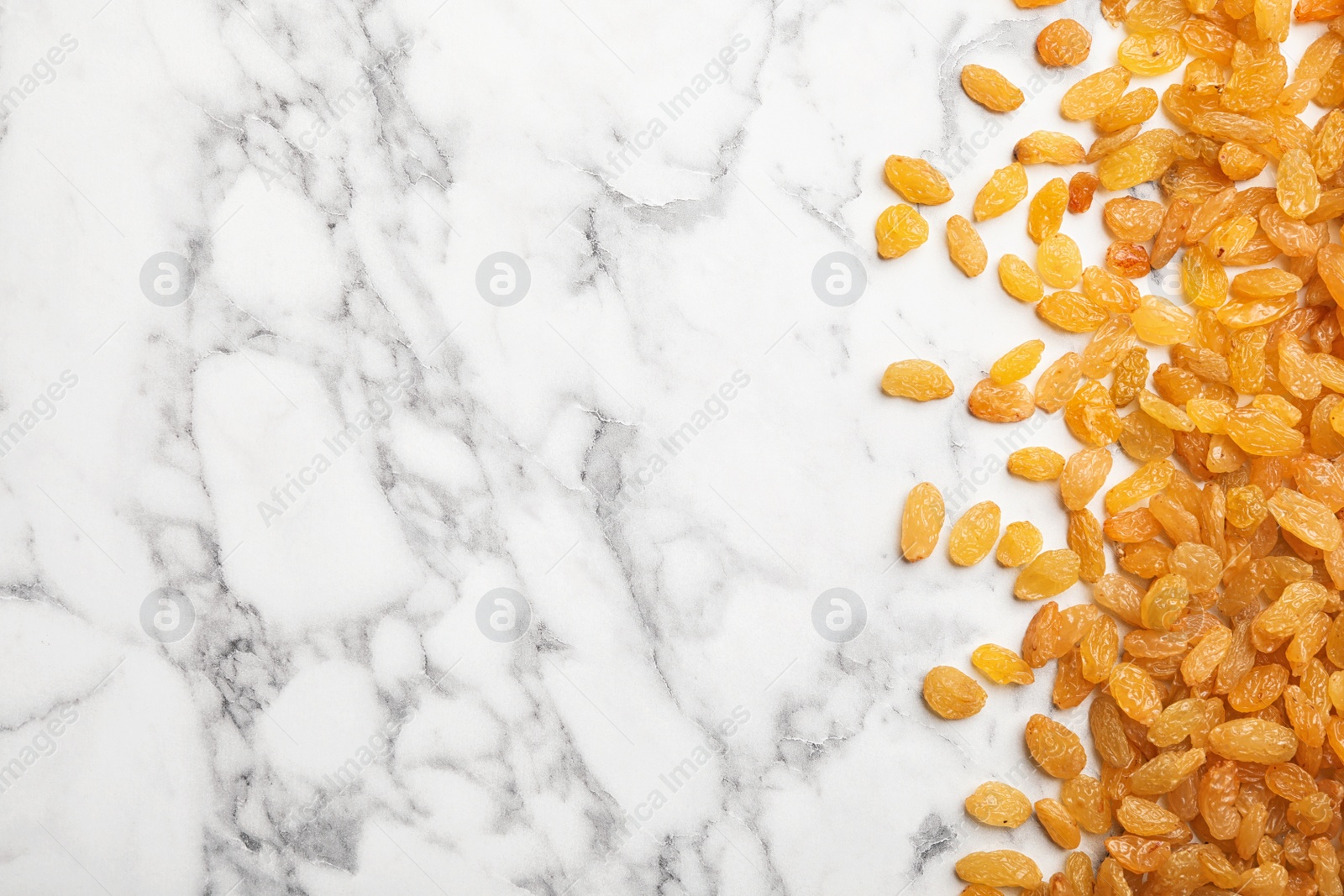 Photo of Many raisins and space for text on marble background, top view. Dried fruit as healthy snack