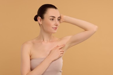 Beautiful woman showing armpit with smooth clean skin on beige background