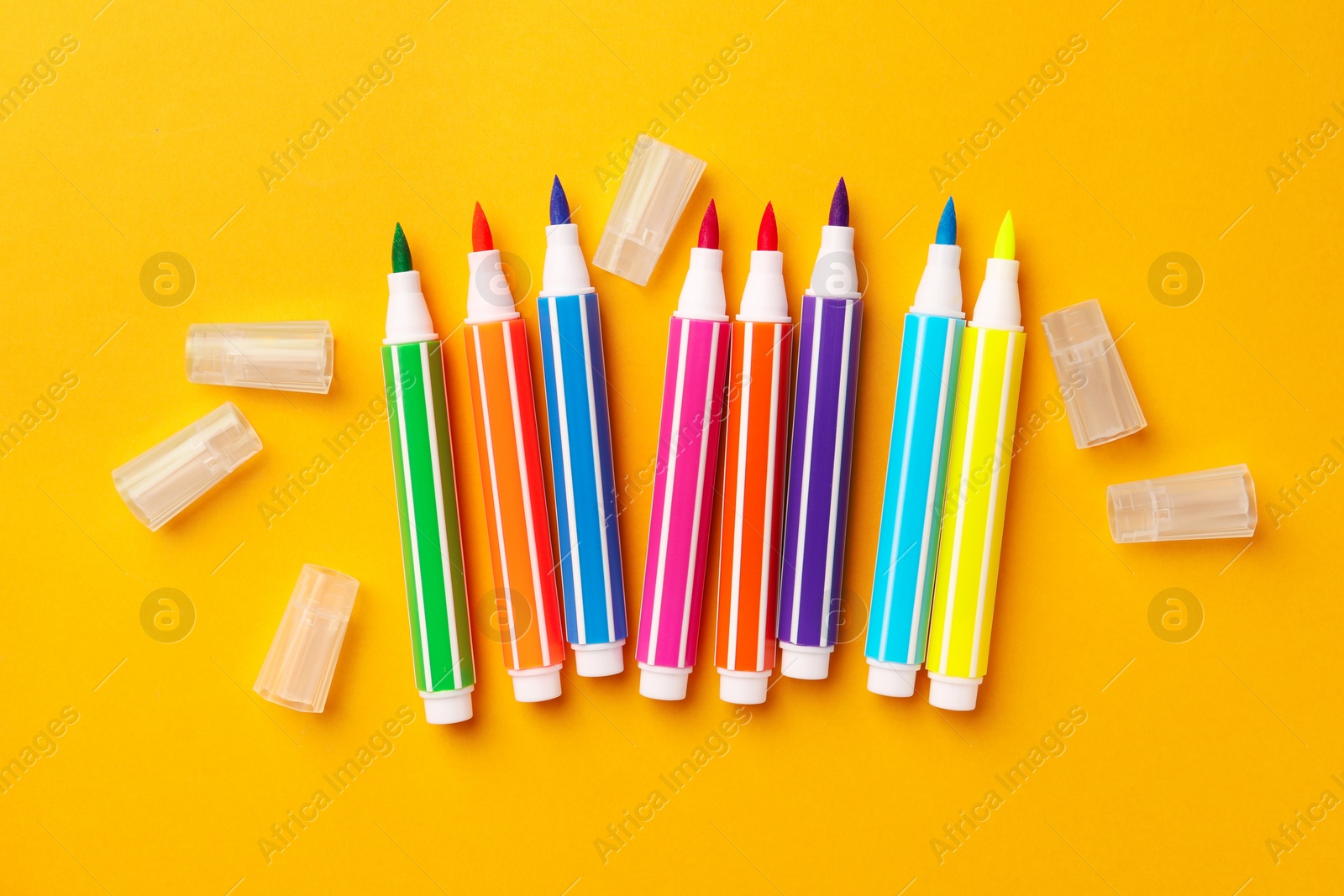 Photo of Many bright markers on yellow background, flat lay