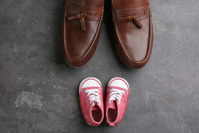 Photo of Dad and daughter's shoes on grey stone background, flat lay. Happy Father's Day