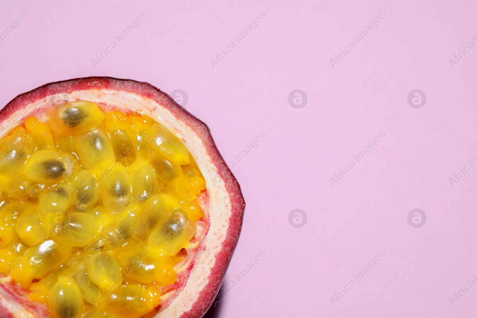 Photo of Half of passion fruit (maracuya) on pink background, top view. Space for text