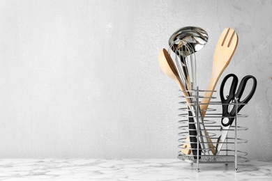 Photo of Different kitchen utensils on table against light background. Space for text