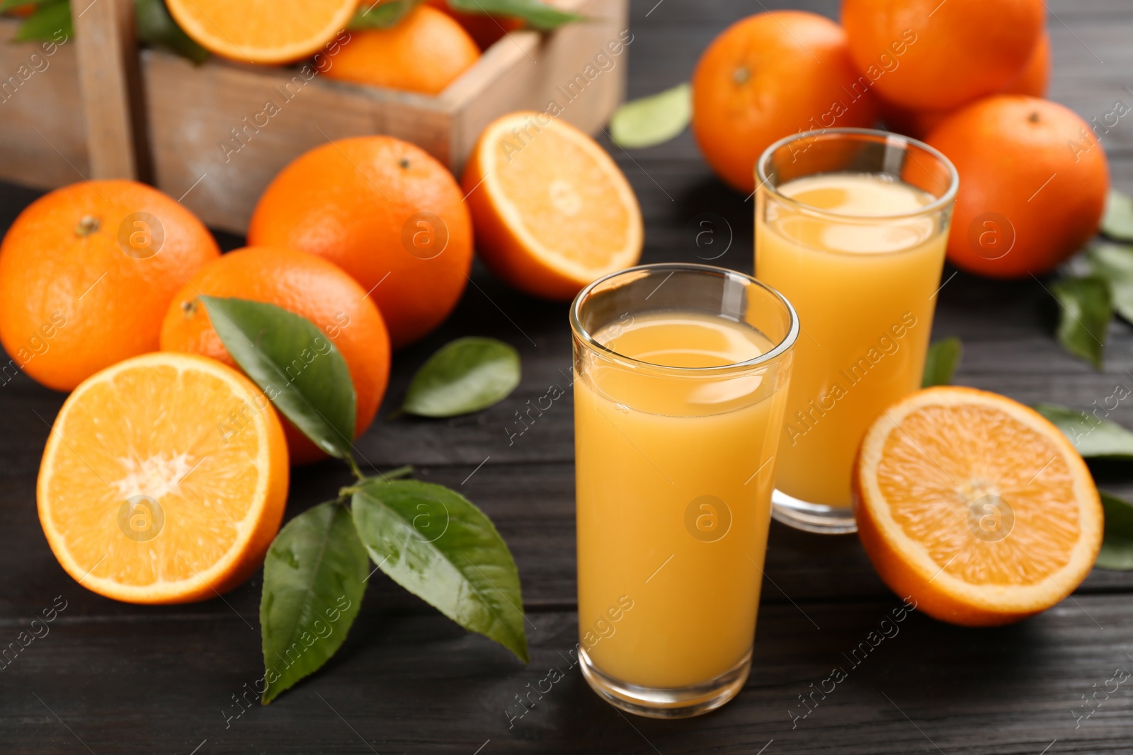 Photo of Delicious orange juice and fresh fruits on black wooden table