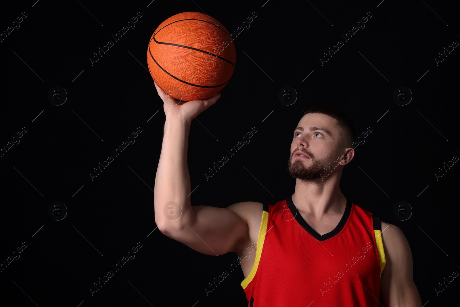 Photo of Athletic young man with basketball ball on black background