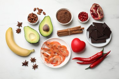 Photo of Natural aphrodisiac. Different food products and red decorative heart on white marble table, flat lay