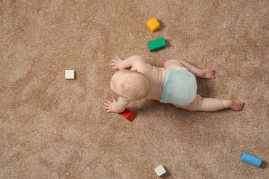 Cute little baby crawling on carpet with toys, top view. Space for text