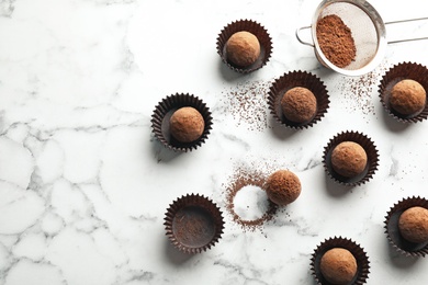 Flat lay composition with tasty raw chocolate truffles on marble background, space for text