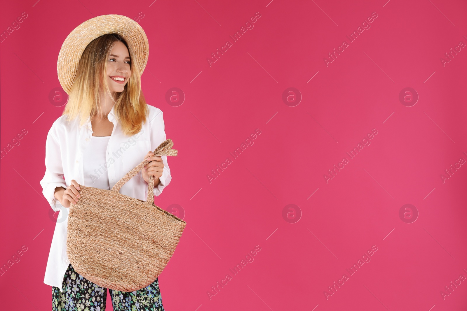 Photo of Beautiful young woman with stylish straw bag on pink background. Space for text