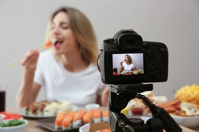 Photo of Food blogger recording eating show against beige background, focus on camera screen. Mukbang vlog