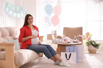 Happy pregnant woman in room decorated for baby shower party