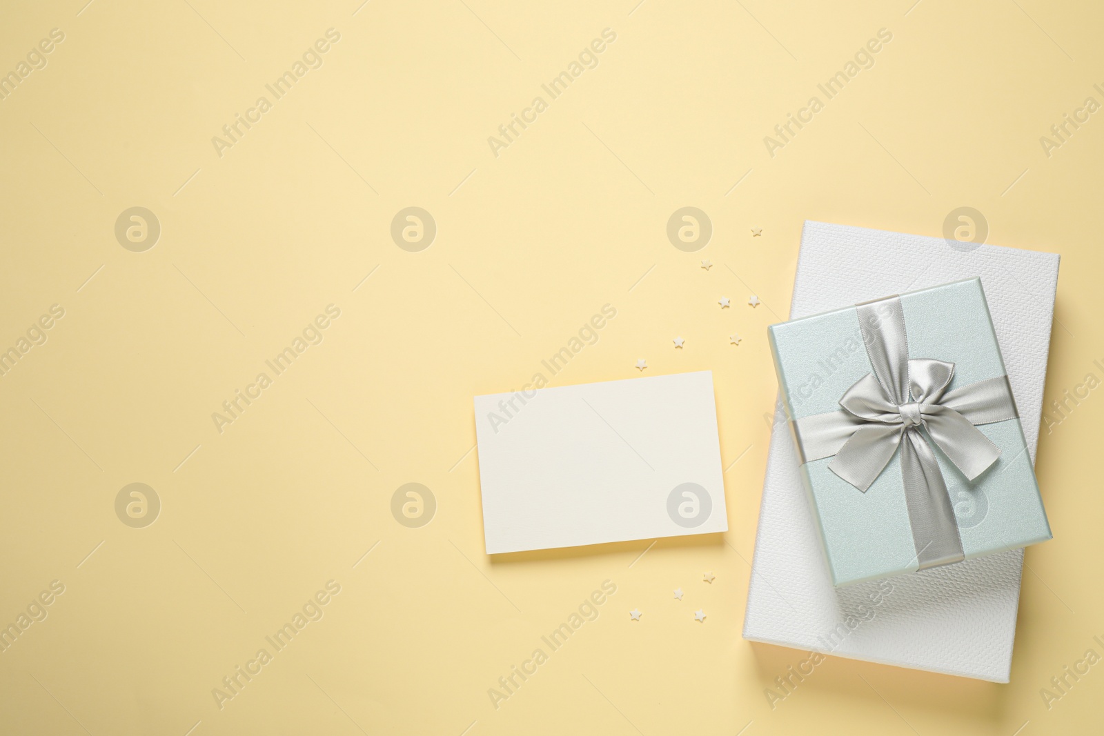 Photo of Beautiful gift boxes and blank card on beige background, flat lay. Space for text