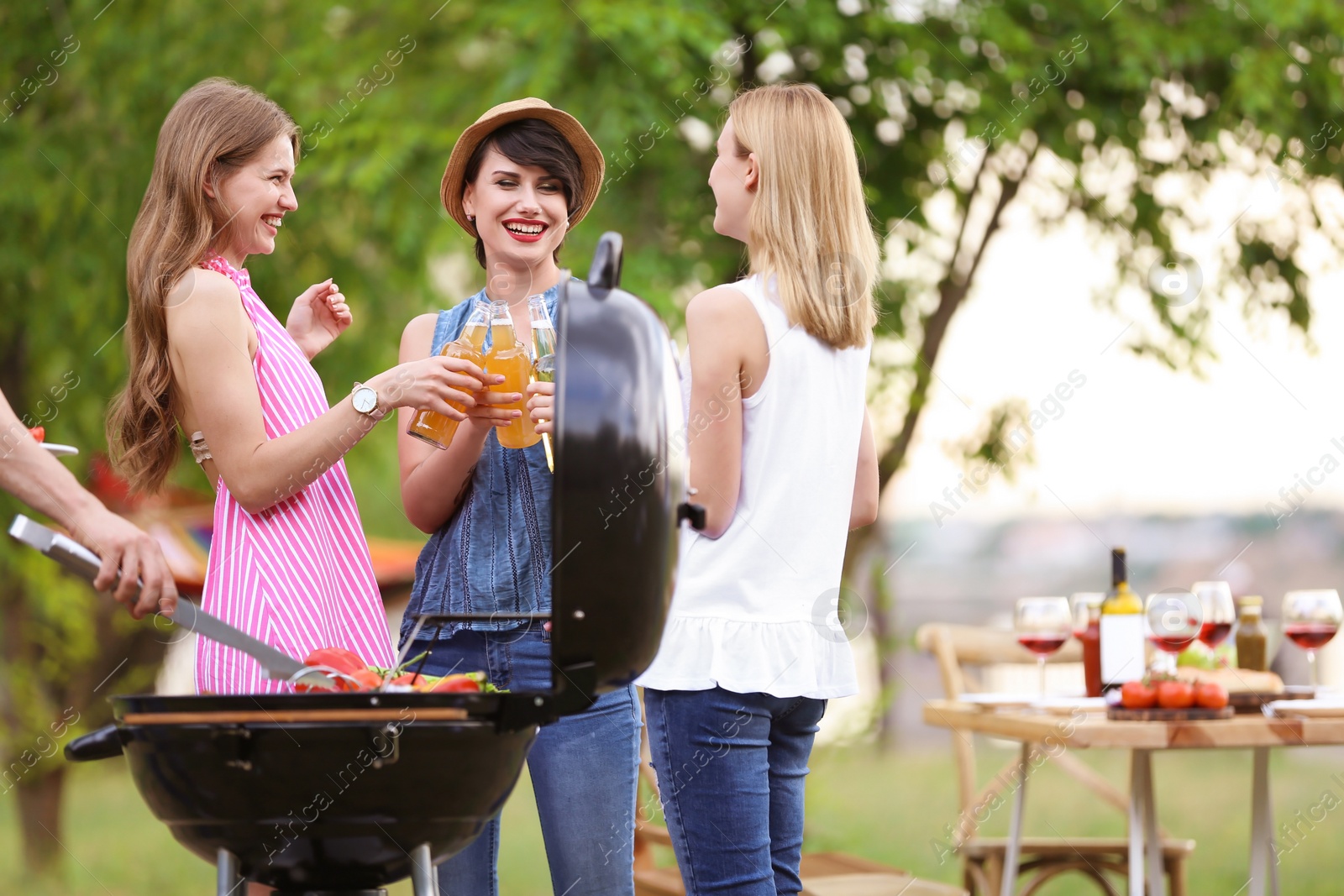 Photo of Young women having barbecue with modern grill outdoors