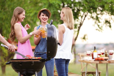 Photo of Young women having barbecue with modern grill outdoors