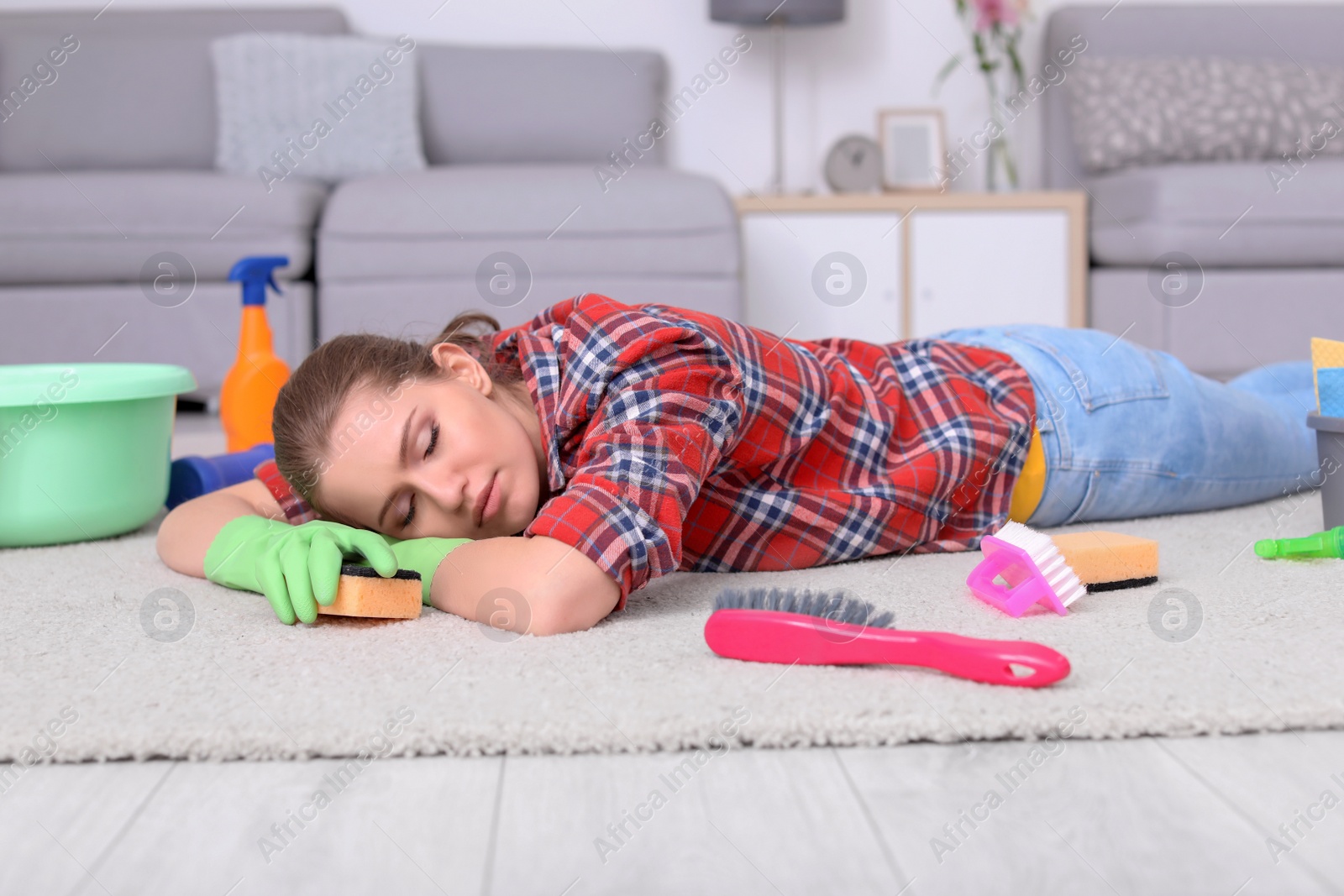 Photo of Tired woman sleeping on floor after cleaning carpet at home