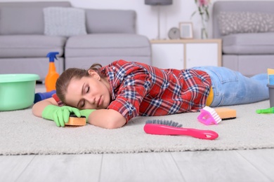 Tired woman sleeping on floor after cleaning carpet at home