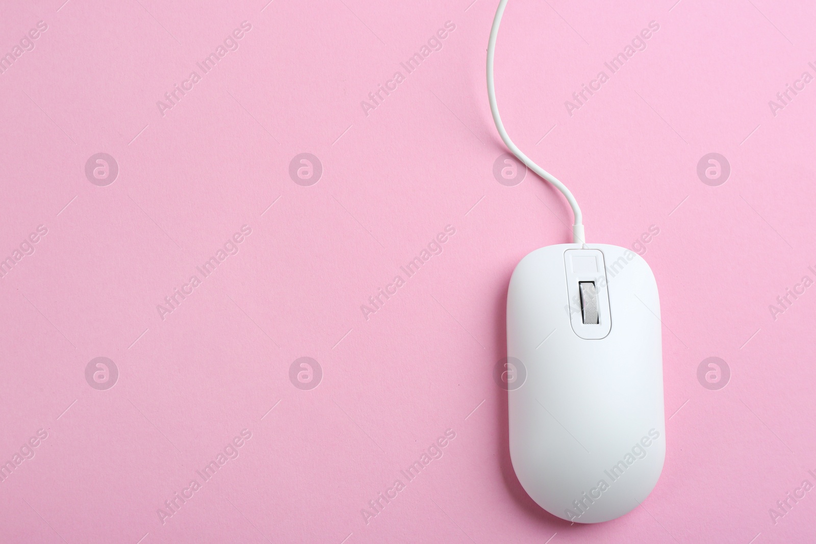 Photo of Modern wired optical mouse on pink background, top view. Space for text