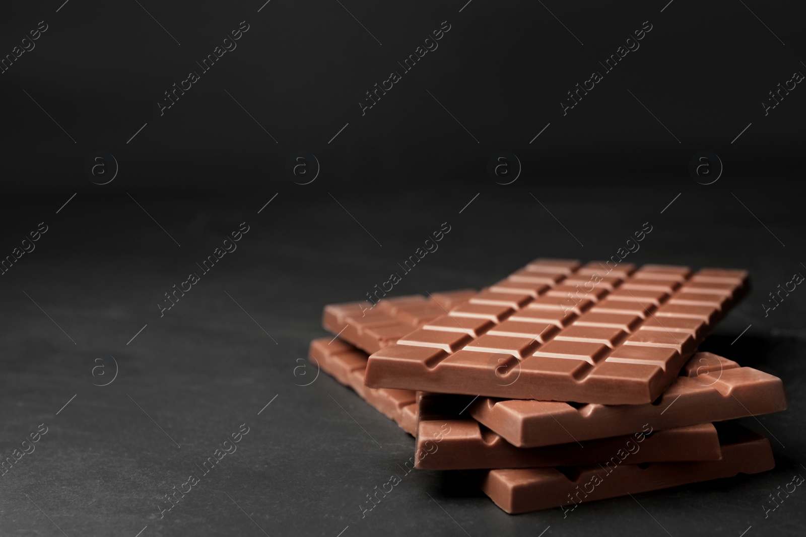 Photo of Tasty chocolate bars on grey table, space for text