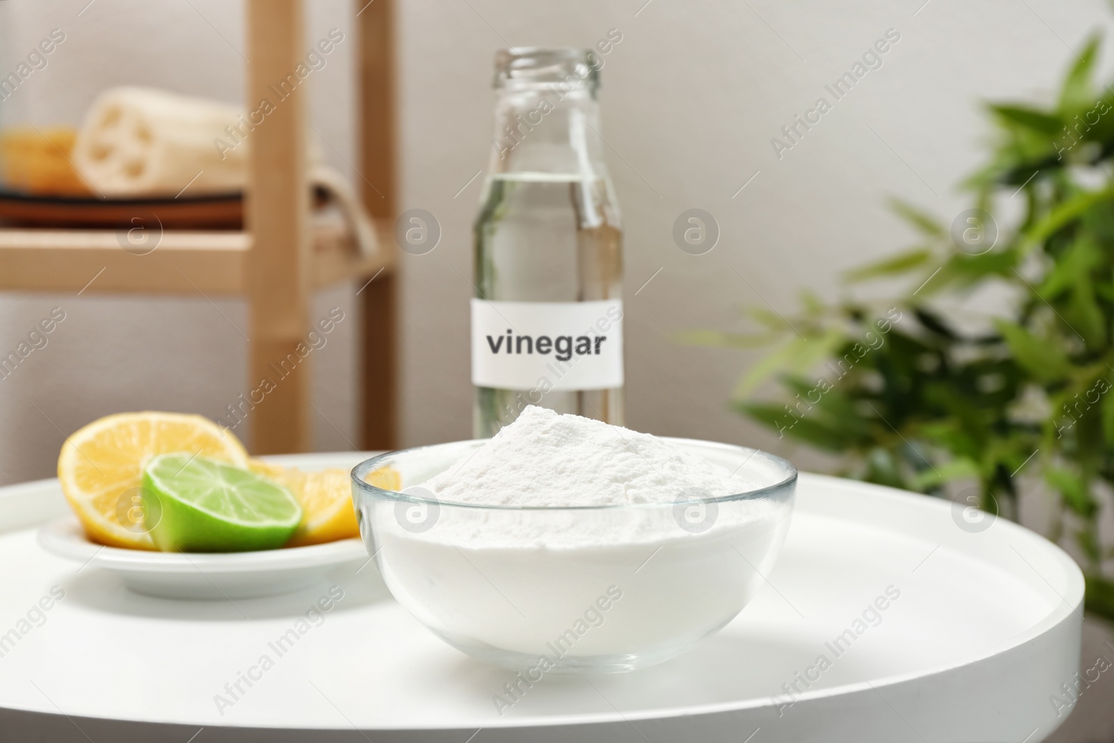 Photo of Bowl with baking soda, lemons and bottle of vinegar on table indoors