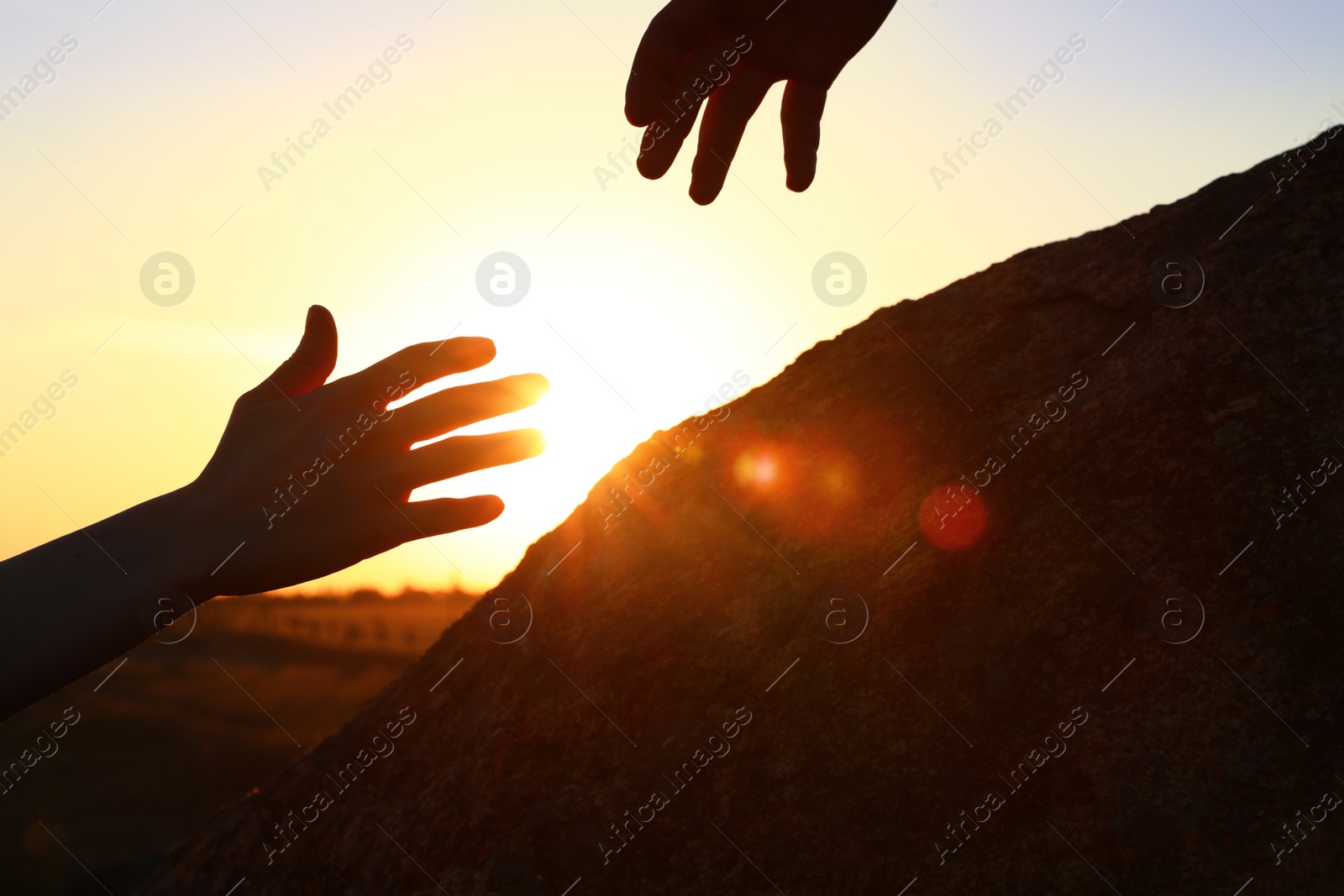 Photo of Hiker helping friend outdoors at sunset. Help and support concept