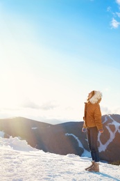 Photo of Happy young woman spending winter vacation in mountains. Space for text