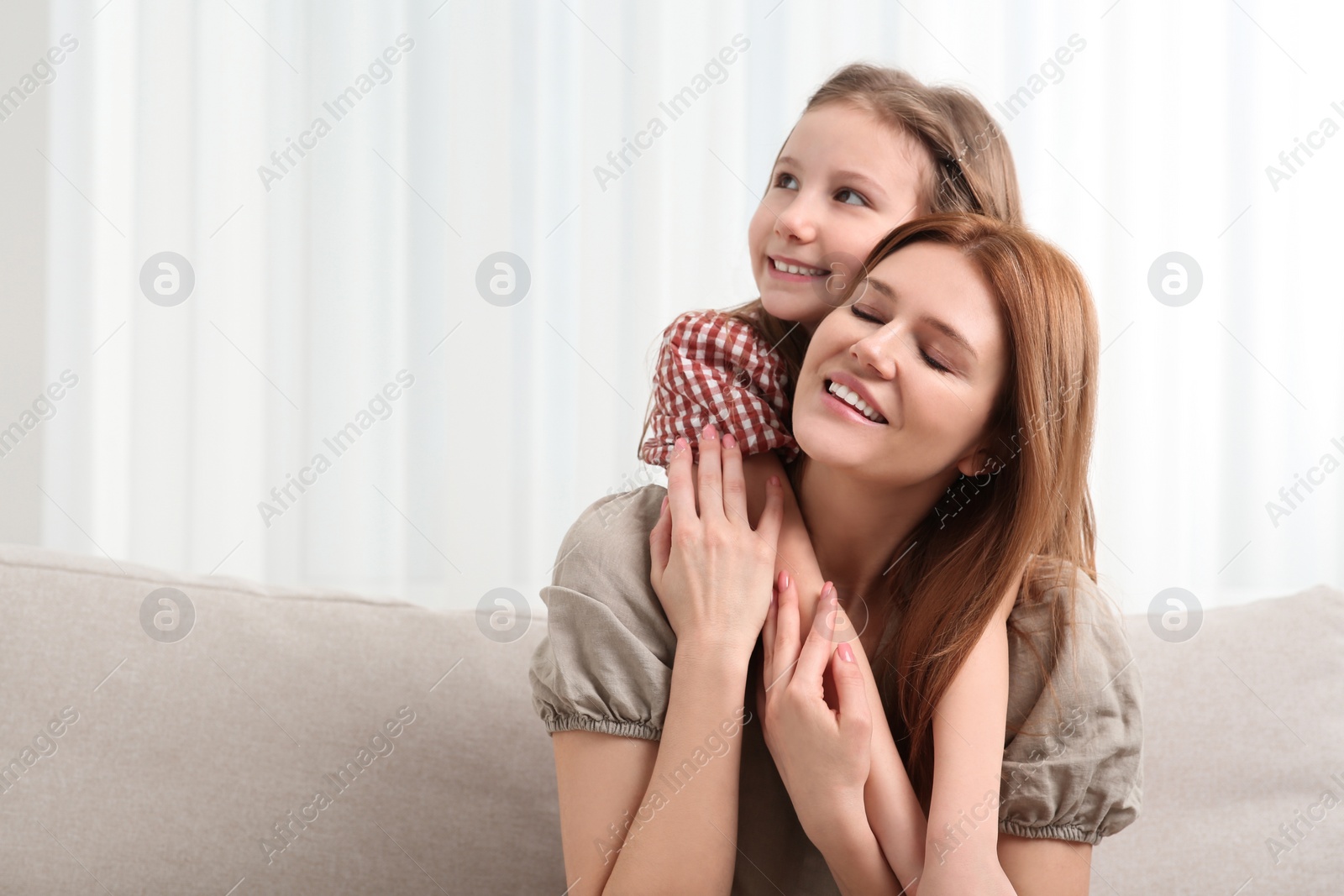 Photo of Happy mother and her cute daughter on sofa at home