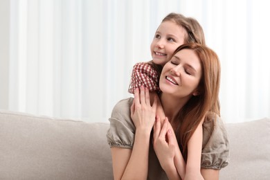 Happy mother and her cute daughter on sofa at home