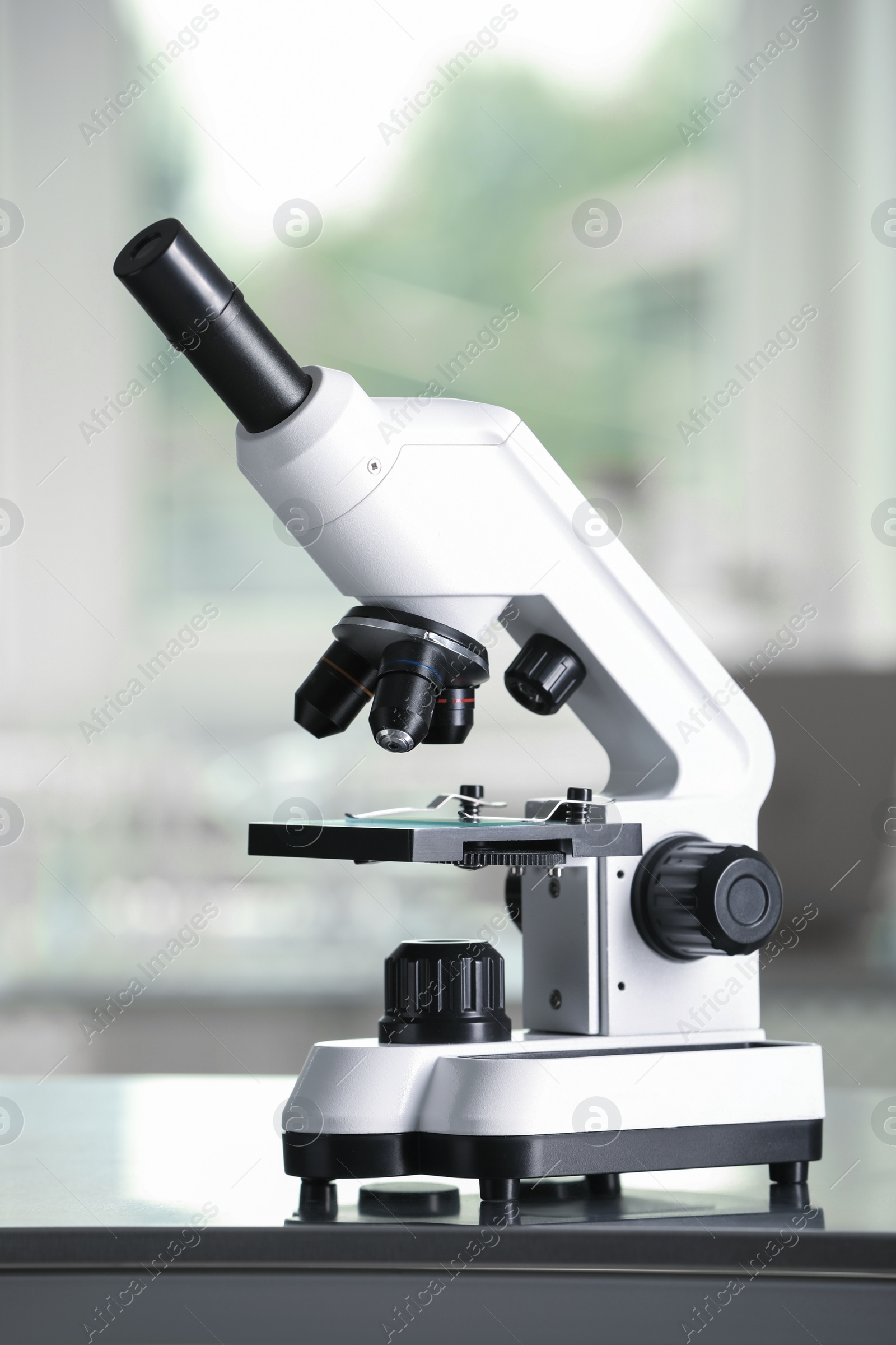 Photo of Modern medical microscope on metal table in laboratory