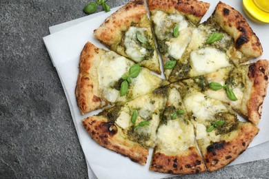 Photo of Delicious pizza with pesto, cheese and basil on grey table, top view